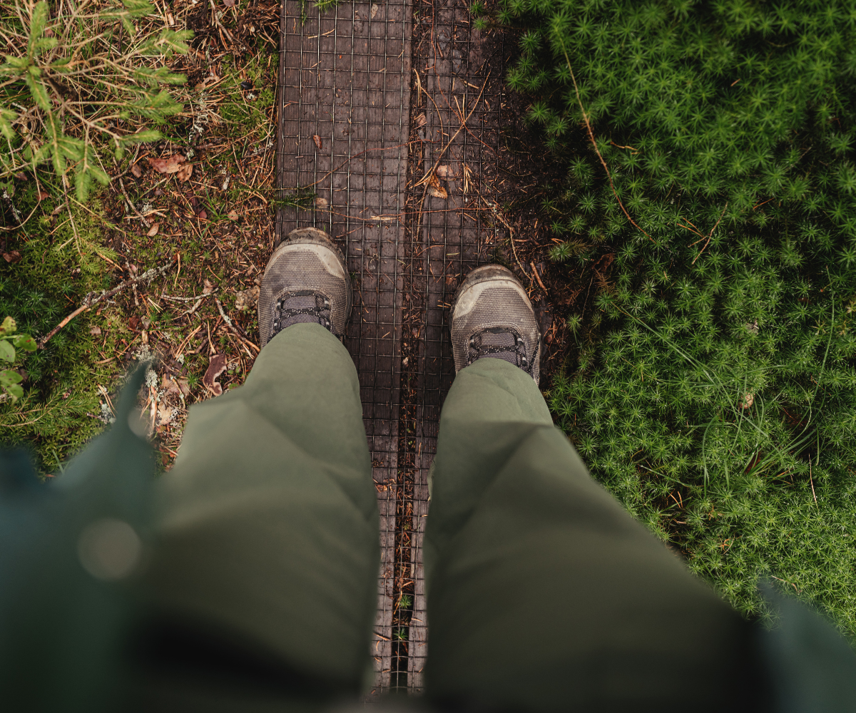 Wanderschuhe auf einem Holzsteg im grünen Moos
