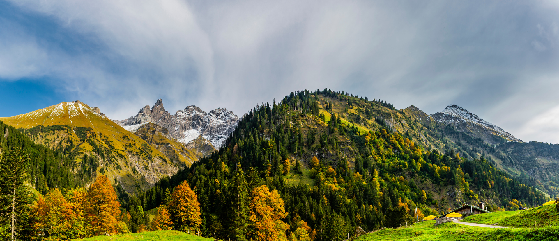 Herbstliche Berglandschaft im Allgäu mit bunten Bäumen und grünen Almwiesen